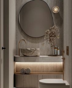 a bathroom with a round mirror above the sink and a white toilet in front of it