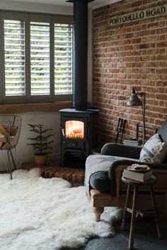 a living room filled with furniture and a fire place next to a brick wall covered in shutters