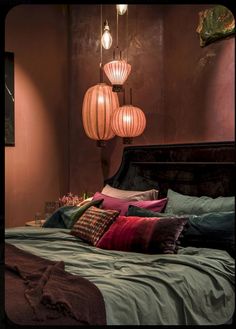 a bed with pillows and lamps hanging from the ceiling