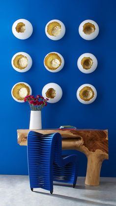 a blue table with some white plates on it and a vase filled with flowers in front of them