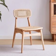 a wooden chair sitting on top of a white rug next to a potted plant