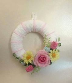 a white wreath with pink and yellow flowers