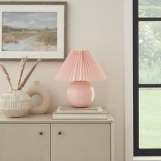 a pink lamp sitting on top of a wooden dresser