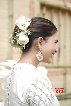 a woman with flowers in her hair wearing a white dress and pearls on the back