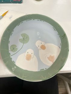 a plate with two ducks painted on the front and back of it, sitting on a table