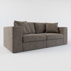 a gray couch with pillows on it sitting in front of a white wall and floor