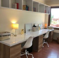 a desk with two chairs and a lamp on it in front of a large window