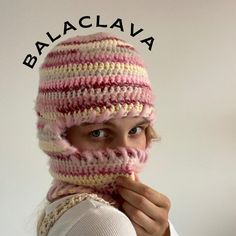 a woman wearing a pink and white striped knitted hat with the word balacava written on it