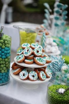 a table topped with lots of desserts covered in blue and green sprinkles