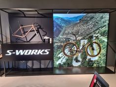 there is a display case with bikes on it in the store front window, and an advertisement for s - works