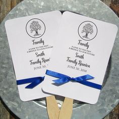 two wedding fans on a plate with blue ribbon tied around the edges and matching names