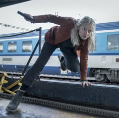 a woman standing on top of a rail near a train