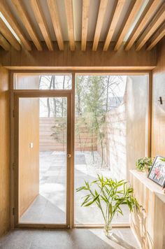 a wooden room with an open door and plants on the shelf in front of it