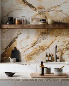 a kitchen with marble counter tops and shelves above the sink is filled with bottles, bowls, and utensils