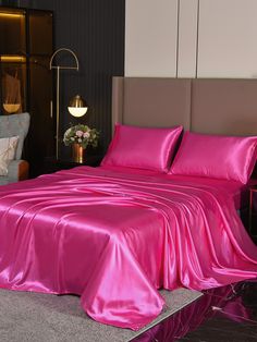 a bed with pink sheets and pillows on top of it in a room next to a chair