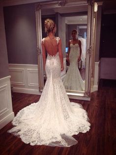 the back of a woman's wedding dress in front of a mirror with her reflection