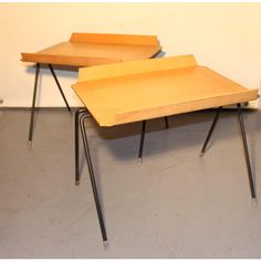 two wooden tables sitting next to each other on metal legs