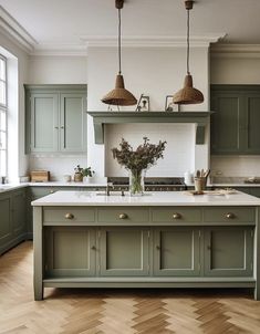 a kitchen with green cabinets and an island in the middle, surrounded by wood flooring