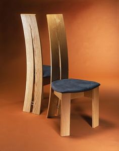 two wooden chairs sitting side by side in front of an orange background, one with a blue seat