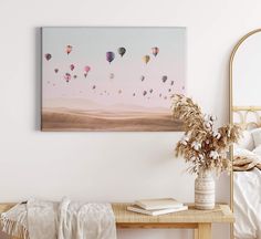 a painting on the wall above a bed with a vase filled with flowers next to it