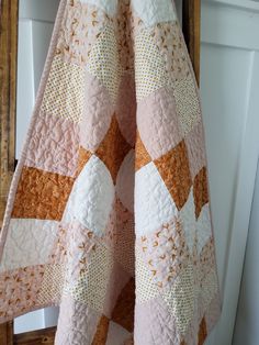 a pink and orange quilt hanging from a wooden ladder