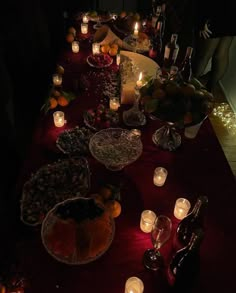 a long table covered with candles and plates filled with food next to bottles of wine