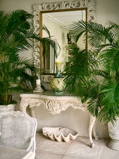 a mirror sitting on top of a white table next to a potted palm tree