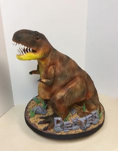 a dinosaur figurine sitting on top of a base with its mouth wide open