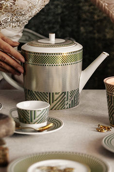 a table topped with plates and cups next to a tea pot on top of a table