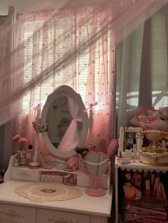 a vanity with a mirror, dresser and pink curtains in the room that is decorated