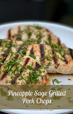 two grilled pork chops on a white plate with green garnishes