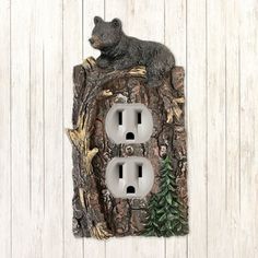 an outlet cover with a bear sitting on it's side and pine trees in the background