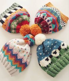 four knitted hats with pom poms on them