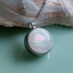 Very pretty opalescent keepsake locket necklace. Consider filling with memorial ashes, a lock of hair or pet fur, or dried special occasion flowers. Fill it with anything meaningful.  *Your keepsake is nicely displayed through the back glass of this 3/4" round locket.  *Lovely opal colors including shades of irridescent pinks and pale greens. Colors appear more vibrant or opaque depending on the lighting. *All stainless-steel base and chain make it nice for everyday wear. No worries about tarnis Hair Pendant, Lock Of Hair, Round Locket, Urn Jewelry, Memory Locket, Urn Necklace, Hair Locks, Urn Necklaces, Human Ashes