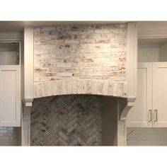 a kitchen with white cabinets and a brick fireplace in the center, surrounded by cupboards