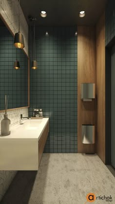 a bathroom with two sinks and green tile on the walls, along with hanging lights