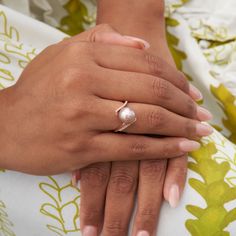 a close up of a person wearing a ring on their hand with a pearl in it