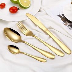 four forks, two spoons and one knife on a white tablecloth with tomatoes