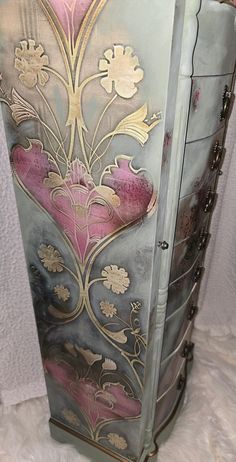 an ornate painted cabinet with flowers and leaves on the front, sitting on white furnishing