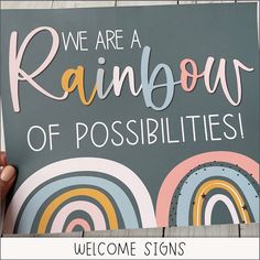 someone holding up a sign that says we are a rainbow of possibilities, welcome signs