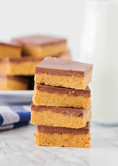 three pieces of peanut butter bars stacked on top of each other next to a glass of milk