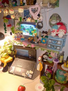 an open laptop computer sitting on top of a wooden desk next to a potted plant