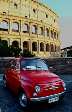 an old red car parked in front of the colossion