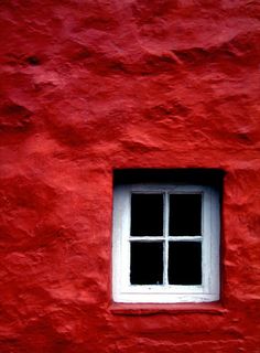 a red building with a white window on it's side and the bottom half is black