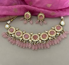 This beautiful pink kundan necklace set with earrings to match has great artistry and will add charm to your attire. It is embedded with kundan and pink stones. The dangling pink beads add a classic sparkle.  Details: Necklace Width-2 Inches Earrings Length-2 Inches Weight of Each Earring-14 gms All products are manufactured using traditional skills from our rich heritage of crafts.  The process of these crafts is essentially manual. Hence, any irregularities or variations are an inherent part of these handcrafting processes. Pink Kundan Necklaces For Gifts, Pink Kundan Necklaces As Gift, Pink Necklace For Diwali, Pink Temple Jewelry Necklace For Diwali, Festive Pink Round Necklaces, Festive Pink Round Necklace, Pink Kundan Necklace For Festivals, Pink Meenakari Necklaces For Festive Occasions, Pink Temple Jewelry Chandbali Necklace