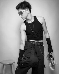 a young man in black and white poses with his foot on a stool wearing sunglasses