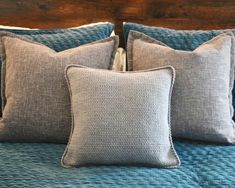 a bed with blue and gray pillows on top of it