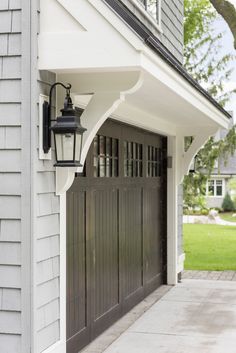 a light on the side of a house next to a garage door and lamp post