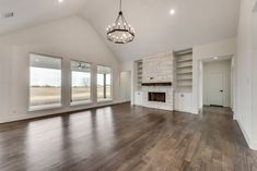 an empty living room with wood floors and large windows in the ceiling, along with built - in bookcases