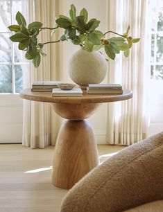 a table with books and a vase on it in the middle of a living room